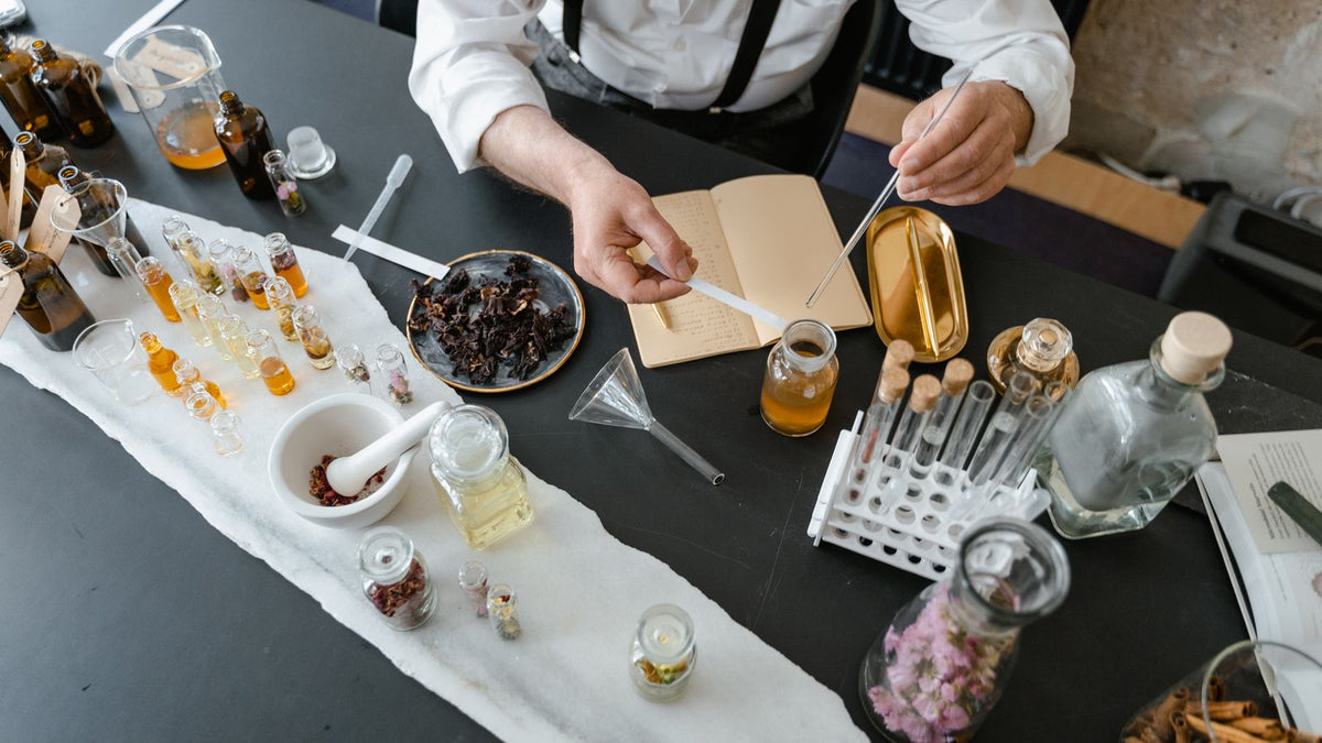 Parfumier lucrând cu ingrediente, mostre și un caiet de notițe, vedere de sus