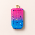 Růžovomodrý flakon Assala Prime Freeze Cool EDP 85 ml s barevným posypem a zlatým rozprašovačem na světlém pozadí – MrRizz